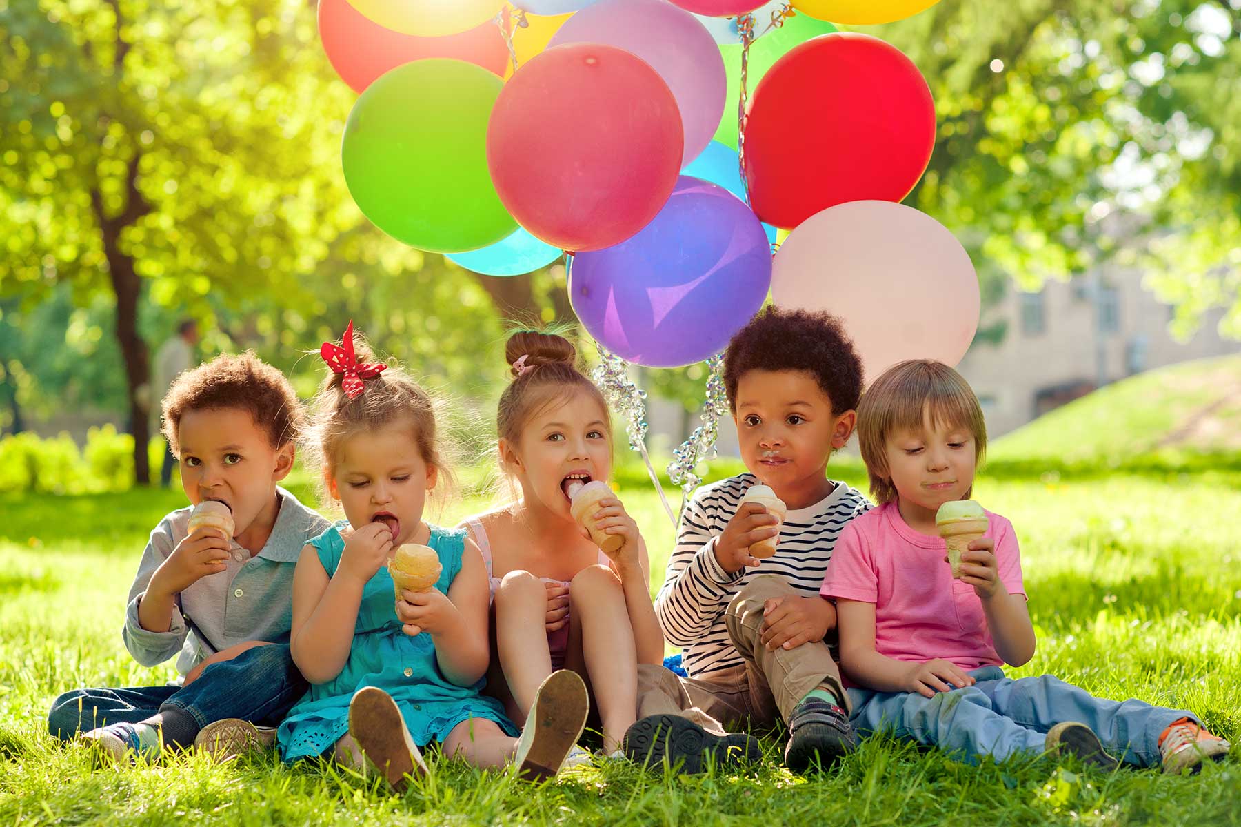 kids at carnival eating ice cream outdoors, balloons in background