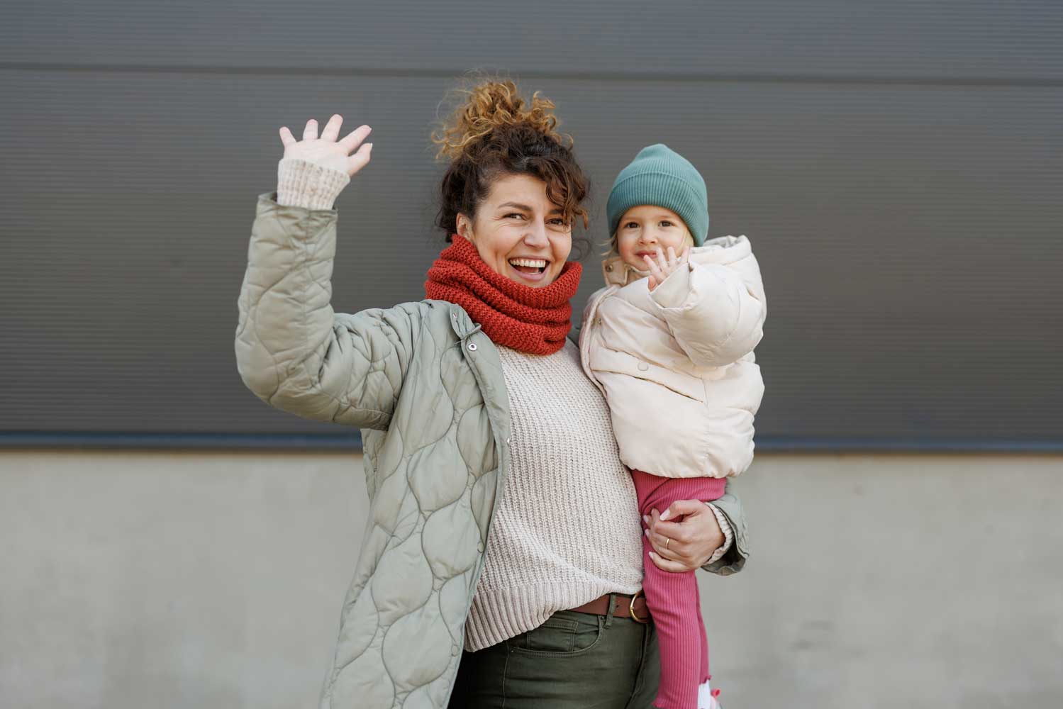 EMAS in Eagan welcoming families, mom holding child, both waving hands